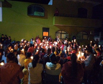 People of El Maguey holding up candles outside at night
